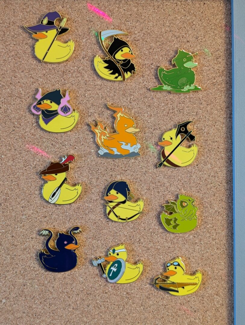 Twelve enamel pins mounted on a corkboard panel, four rows of three, each pin a different Dungeons And Dragons themed design (wizard, bard, various monsters, etc).
